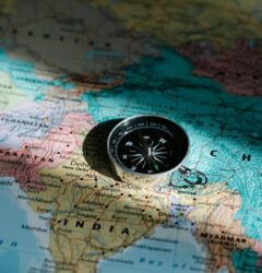 Close-up image of compass on a world map highlighting travel direction and exploration.